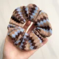 Close-up van de Fair Isle vintage gebreide scrunchie met blauwe en bruine patronen - Haarelastiek / Blauw Koffie Patchwork