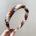 Gedetailleerd overzicht van een retro gebreide hoofdband met geometrische patronen. - Rode Geribbelde Stof / Oranje Koffie Gemengd