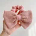 Gros plan d'un chouchou à nœud tricoté rose montrant les détails de la texture en laine - Style Noeud Couleur Unie / Rose