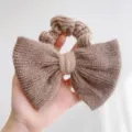 Gedetailleerd overzicht van zachte gebreide strik scrunchie in taupe nertswol textuur - Effen Kleur Strik Stijl / Khaki