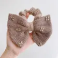 Detailopname van een pluizige strik-scrunchie met gouden stervormige metalen studs - Vijfpuntige Ster Stijl / Khaki