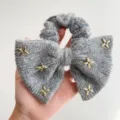 Detail van een grijze nertswollen bow scrunchie met gouden ster strass versiering. - Vijfpuntige Ster Stijl / Lichtgrijs