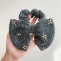 Gedetailleerde weergave van een pluizige grijze strik scrunchie met gouden sterhangers - Vijfpuntige Ster Stijl / donkergrijs
