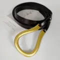 Close-up of women's dark brown genuine leather belt featuring a unique large gold horseshoe buckle. - Coffee