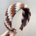 Gedetailleerde macro-opname van gebreide Fair Isle hoofdband in bruin en wit patroon - Brede Hoofdband / Oranje Koffie Gemengd
