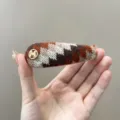 Detail van een retro gebreide haarclip met Fair Isle-patroon en goudkleurig M-embleem - Waterdruppel Clip / Oranje Koffie Gemengd