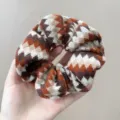 Detailopname van een retro gebreide scrunchie met een Fair Isle zigzagpatroon - Haarelastiek / Oranje Koffie Gemengd