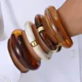 Gros plan de bracelets en acrylique vintage ambre et crème avec des accents en métal doré - Ensemble de 4 Bracelets Joncs en Résine Marbre Ambre et Écaille de Tortue (6672701HB) / Lot de 4 / Ambre