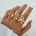 Detailansicht eines goldfarbenen Ring-Sets mit Seestern- und Muscheldesign an der Hand - Seestern und Muschel Stil (6718801HB) / 4-teiliges Set