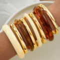 Détail de joncs empilés en acrylique ambre et métal doré montrant le style rétro de l'ensemble - Ensemble de 3 Bracelets Épais Or/Résine Mixte (6661801HB)