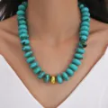 Close-up of chunky turquoise acrylic beaded necklace with central gold bead on model - Turquoise Beaded Style (6780902HB)