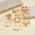 Primer plano de un set de 8 anillos dorados de moda con detalles de serpiente y perlas - Estilo de Perla (5929201)