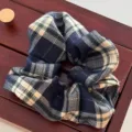Eleganter retro marineblau-weißer karierter Woll-Haargummi auf dunklem Holzhintergrund - Marineblaues Karomuster (3900-5)