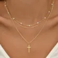 Collier doré multicouche avec perles et pendentif croix porté par un modèle - Style Perle Croix (5727401HB)