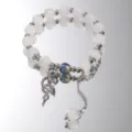 Detailed view of iridescent glass bead and butterfly charm on a white beaded bracelet - White And Blue