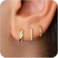 Tres pendientes de aro huggie de cobre dorado con circonitas puestos en la oreja - Juego de pendientes dorados con textura retorcida y pavé (6463101HB) / 6.09