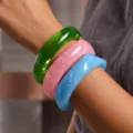 Vista detallada de tres pulseras anchas de resina de colores apiladas en una muñeca - Brazalete de Resina (6825001)
