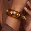 Pulsera ancha de resina ámbar con tachuelas metálicas doradas pulidas para un estilo moderno - Brazalete de Remaches de Acrílico (6851501)