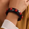 Elegante brazalete de resina acrílica negra con detalles de tachuelas rojas redondas - Brazalete de Remaches de Acrílico (6851503)