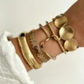 Trendy set of five gold-plated layered bracelets featuring wave and disc charms on wrist - 5-Piece Set - Irregular Wave (6475701HB) / Gold