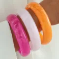Vista detallada de tres pulseras de resina apilables con textura de mármol rosa y naranja. - Brazalete Ancho de Resina para Apilar (6815901)