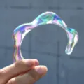 Brazalete ondulado de resina acrílica iridiscente sostenido por la mano - Estilo Irregular Iridiscente (6725105)
