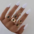 Primer plano de anillos boho dorados con piedras de ojo de tigre en mano con uñas blancas. - Juego de Anillos de Girasol Ojo de Tigre (6717401HB)