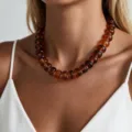 Elegante collar bohemio de cuentas gruesas color ámbar lucido por una modelo para la playa - Estilo de Cuenta Plana Redondeada (6780303HB) / Marrón Oscuro