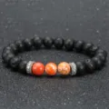 Schwarzes Lavastein und orangener Jaspis Perlenarmband mit silbernen Mantra-Abstandshaltern. - Lavastein und Oranger Naturstein mit Silber Perlen