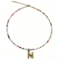 Dettaglio della collana di perline colorate con ciondolo a lettera N color oro chic. - Lettera N
