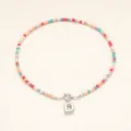 Gros plan détail du collier bohème en perles colorées avec pendentif argenté lettre D. - Lettre D / Acier