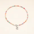 Gros plan détaillé du collier de perles colorées style bohème avec pendentif lettre en acier inox. - Lettre G / Acier