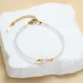 Delicate kristalen kralenarmband met een centrale parel en gouden accenten. - Transparant