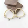 Nahaufnahme passender Magnet-Paararmbänder mit Berg- und Wellenanhängern an beigen Seilen. - Beige