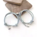Vue détaillée des bracelets tressés magnétiques de couple avec des pendentifs en métal. - Gris