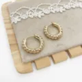 Macro view showing the intricate twisted texture of gold-plated hoop earrings on velvet - Twisted Texture (1) / Gold