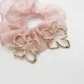 Detailed view of oversized golden geometric flower earrings with hammered texture. - Irregular Floral Marine Geometric (13)
