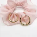 Close-up of elegant chunky gold hoop earrings resting on soft pink ruffled fabric decor - High Polished Large Hoop (11)