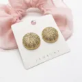 Detailed view of gold sea urchin textured stud earrings on a jewelry display card. - Sea Urchin Textured Half Round (8)