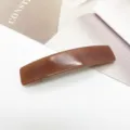 Vue détaillée d'une barrette rectangulaire en acétate marron brillant sur fond minimaliste - Brun Brillant (7)