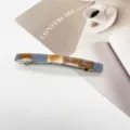 Macro view of minimalist marbled resin rectangular spring barrette for hair styling - Color Block Marble Pattern