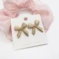 Detailed view of vintage gold textured bow-tie stud earrings on white jewelry card - 3D Striped Vintage Bowknot (26)