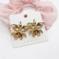 Detailed view of golden orchid flower stud earrings on a white jewelry display card. - Orchid Shape Wavy Texture (24)