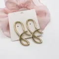 Close-up of gold-plated geometric abstract wavy stud earrings on a display card - Streamlined Irregular Lines (17)