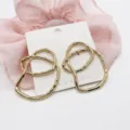 Close-up detail of gold irregular geometric alloy stud earrings with shiny finish - Double Loop Nested Fluid Geometric (16)