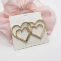 Detailed shot of elegant gold-toned double heart stud earrings on display card. - Overlapping Double Heart Geometric (15)