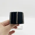 Close-up detail of black pleated fabric ponytail hook clip with rows of rhinestones - Black