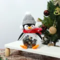 Primo piano di un barattolo di caramelle natalizio a forma di pinguino di peluche. - Barattolo di caramelle pinguino con cappello grigio
