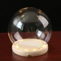 Détail de dôme en verre sur socle en bois LED avec verre clair et éclairage chaleureux. - Boule ronde 15 cm + veilleuse tactile à fente