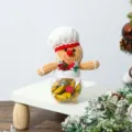 Close-up of a festive gingerbread man plush candy jar on a white display riser for Christmas. - Gingerbread Man Candy Box Chef Hat